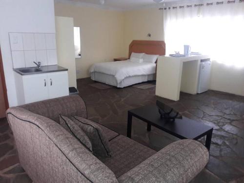 a hotel room with a bed and a couch and a table at Murangi Travel Lodge in Windhoek