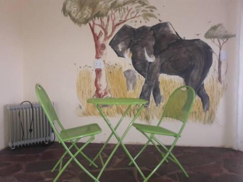two green chairs in front of a painting of an elephant at Murangi Travel Lodge in Windhoek