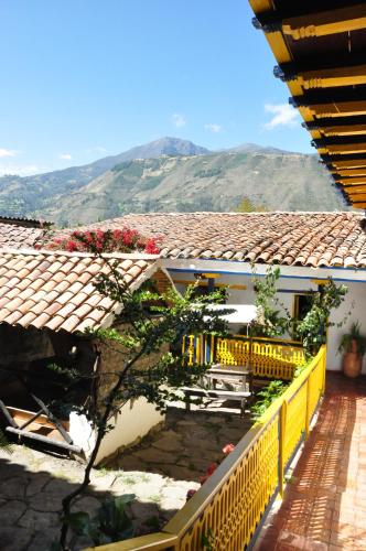 a house with a yellow fence and mountains in the background at Hotel Museo la Posada del Molino in El Cocuy