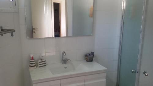 a white bathroom with a sink and a mirror at A Place To Remember in Ma‘alot