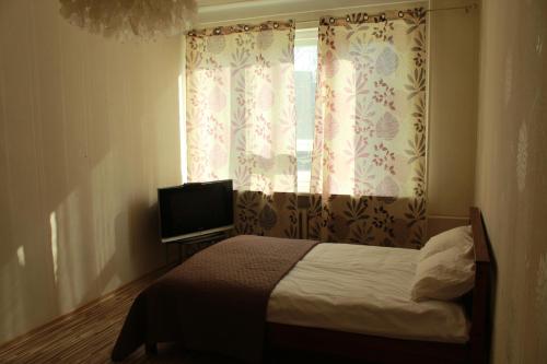 a bedroom with a bed and a window with a television at Happy Day in Narva