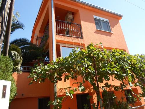 un edificio naranja con un árbol delante de él en Holiday home Orange family apartments en Utjeha