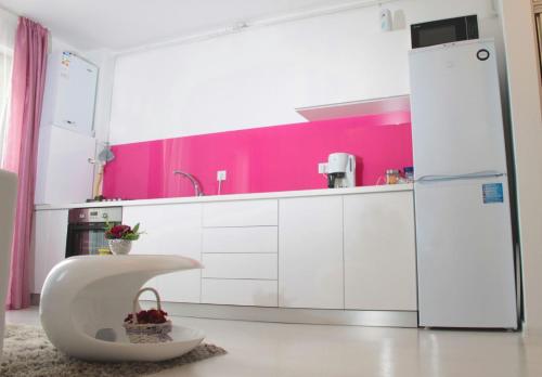 a kitchen with white cabinets and a pink wall at White Luxury Apartment in Sibiu