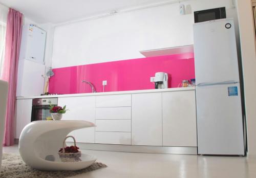 シビウにあるWhite Luxury Apartmentのピンクの壁のキッチン(白いキャビネット付)