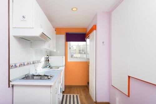 サン・イシドロにあるEstudio moderno y acogedor, a 5 minutos de la playaの白いキャビネットとオレンジ色の壁が備わるキッチン