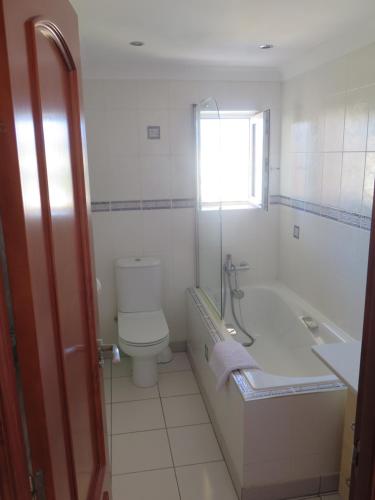 a bathroom with a toilet and a tub and a window at Pl Les Bovetes Apt in Denia