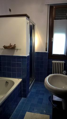 baño de azulejos azules con bañera y lavamanos en Le Betulle, en Zanica