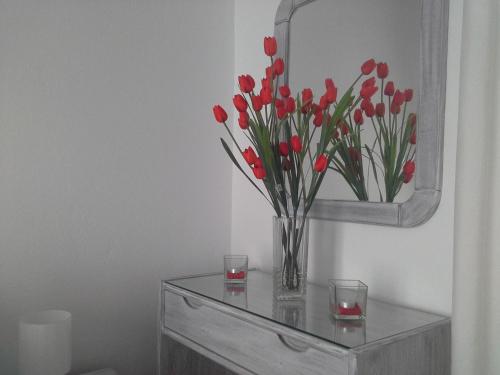 a vase of red tulips on a table with a mirror at Kiklamino Sunset Studios in Oia