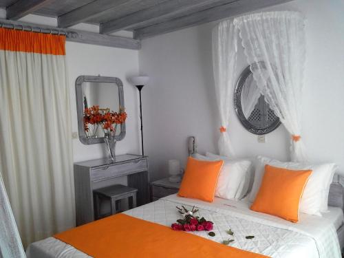 a bedroom with a bed with orange pillows and a mirror at Kiklamino Sunset Studios in Oia