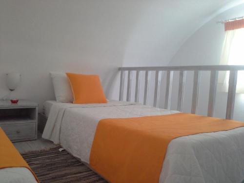 a bedroom with two beds and an orange pillow at Kiklamino Sunset Studios in Oia