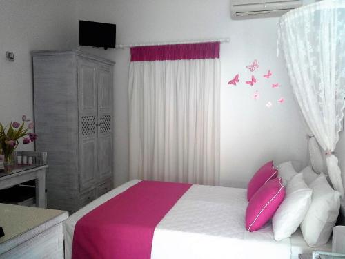 a bedroom with a bed with pink and white pillows at Kiklamino Sunset Studios in Oia