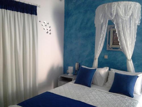 a bedroom with a bed with a canopy and blue walls at Kiklamino Sunset Studios in Oia