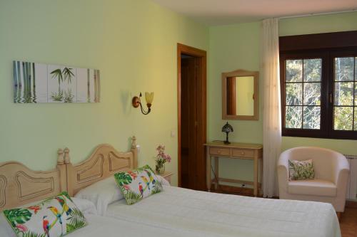 a bedroom with two beds and a chair and a window at Las Anjanas de Isla in Isla