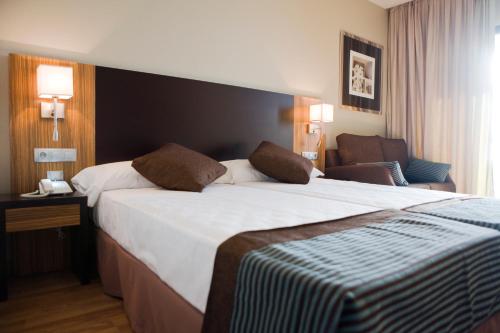 a hotel room with a large bed and a chair at Hotel y Apartamentos Conilsol in Conil de la Frontera