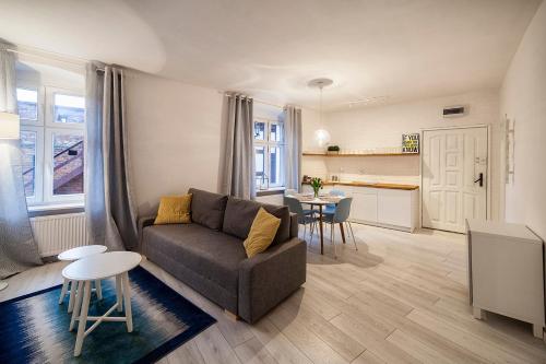 a living room with a couch and a kitchen at Apartamenty toruńskie pod Krzywą Wieżą in Toruń