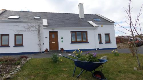 a white house with a wheelbarrow in front of it at Rossroe Lodge B&B in Canower