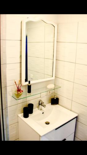 une salle de bain blanche avec un lavabo et un miroir dans l'établissement Le Moment Bleu, à Strasbourg