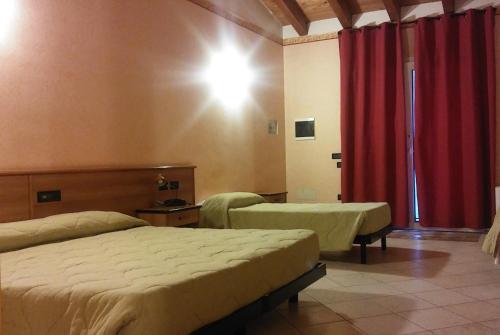 a bedroom with two beds and a red curtain at Hotel Tolin in Ronco allʼAdige