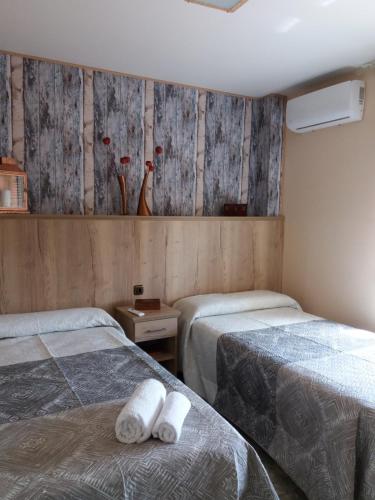 two beds in a room with wooden walls at Quevoy in Alcañiz