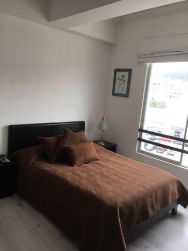 a bedroom with a large bed with a large window at Suites Parque Real in Quito