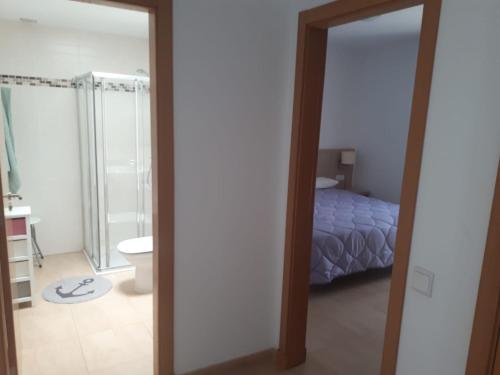 Un dormitorio con una cama y un baño con espejo. en Fuerteventura Port Sea, en Morro del Jable