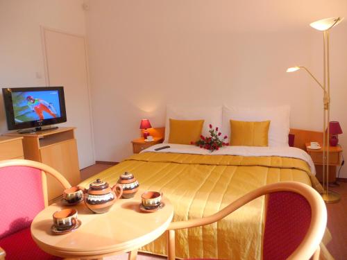 a bedroom with a bed with a table and a television at BALATON ART Guesthouse in Balatonszemes
