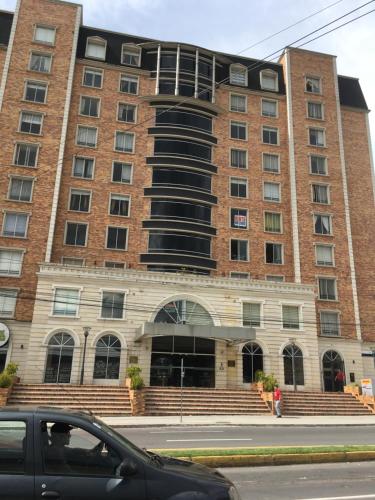 a building with a car parked in front of it at Suites Parque Real in Quito