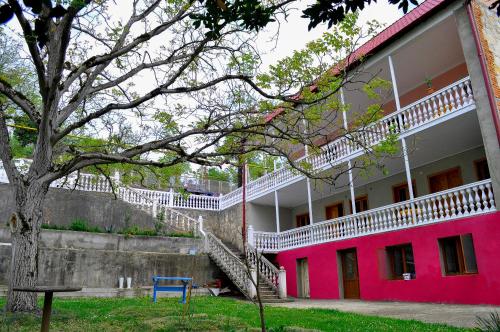 een roze gebouw met een trap en een blauwe stoel bij Sofia Guest House in Koetaisi