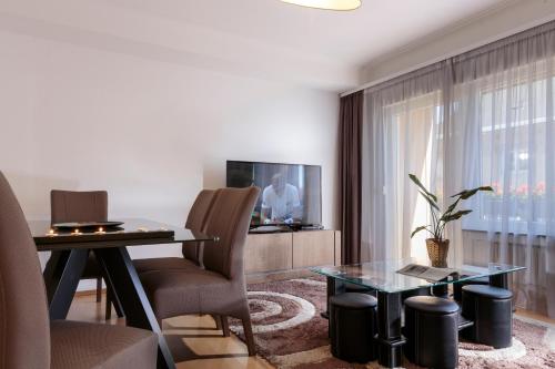 a living room with a table and a tv at The Queen Luxury Apartments - Villa Carlotta in Luxembourg