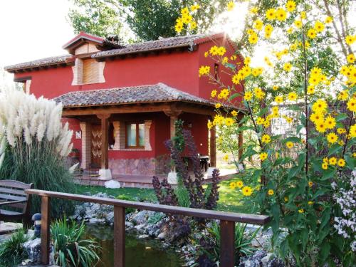 een rood huis met gele bloemen in de tuin bij A Toca Casas Rurales en Turegano Segovia in Turégano