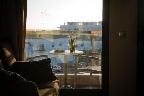 a table with a bottle of wine on top of a window at Hotel y Apartamentos Conilsol in Conil de la Frontera