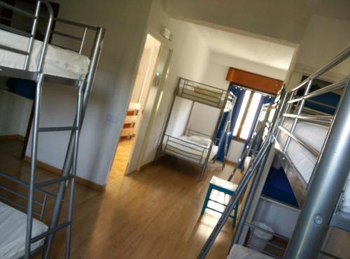 a room with several bunk beds and a room with a hallway at Albergue Puente para peregrinos in Puente la Reina