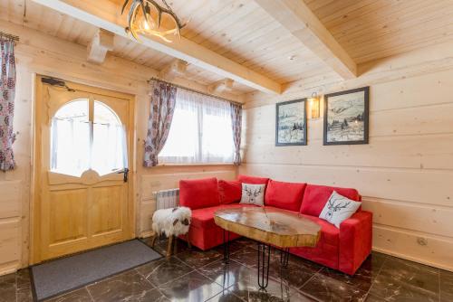 a living room with a red couch and a table at Domki u Magdy in Zakopane
