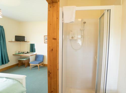 a bathroom with a shower and a bed and a desk at Fortview Guest House in Enniscrone