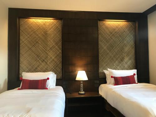 a hotel room with two beds and a lamp at Elliebum Boutique Hotel in Chiang Mai