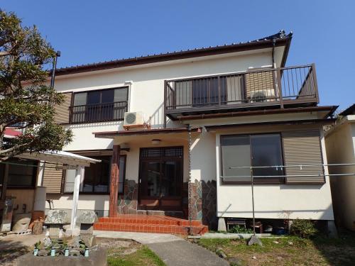 a white house with a balcony on top of it at Guesthouse SORA in Minamiizu