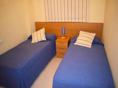 una camera con due letti e un comodino di Apartamento Brisas de Denia a Denia