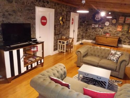 a living room with couches and a flat screen tv at Vila Vinha in Arco da Calheta