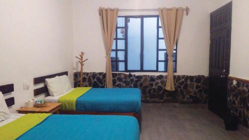 a hotel room with two beds and a window at Hotel Falcon in Tamasopo