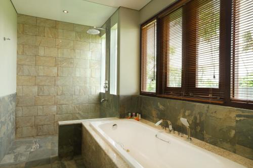 a large bathroom with a tub and windows at Best Western Premier Agung Resort Ubud in Ubud
