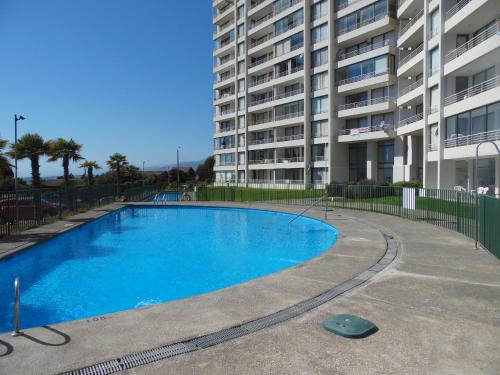 a swimming pool in front of a large apartment building at Laura Barros, Con Con in Concón