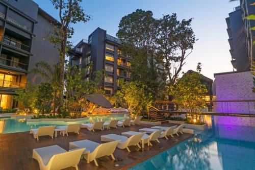 a pool with tables and chairs next to a building at Panan Krabi Resort in Ao Nang Beach