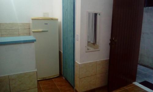 y baño con nevera y espejo. en Apartamento Da Praça, en Arraial do Cabo