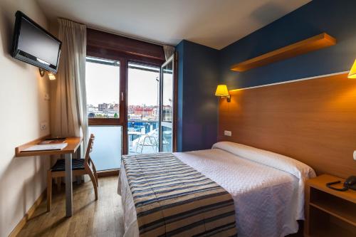 Habitación de hotel con cama, escritorio y ventana en Hotel La Polar, en Gijón