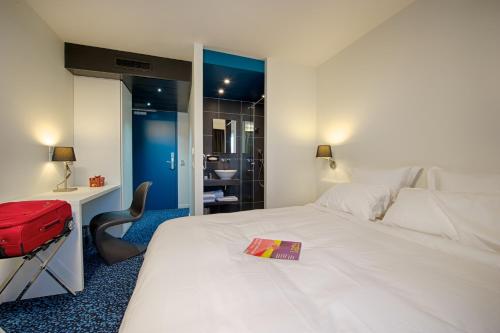 a hotel room with a white bed and a red suitcase at Nex Hôtel in Tarbes