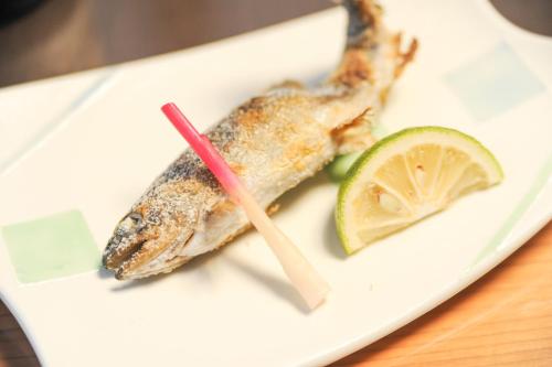 a plate with a piece of fish and a lime at Yamashinobu in Minamioguni