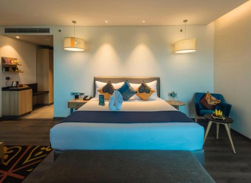 a bedroom with a large blue bed and a chair at Grand Mercure Mysore - An Accor Brand in Mysore
