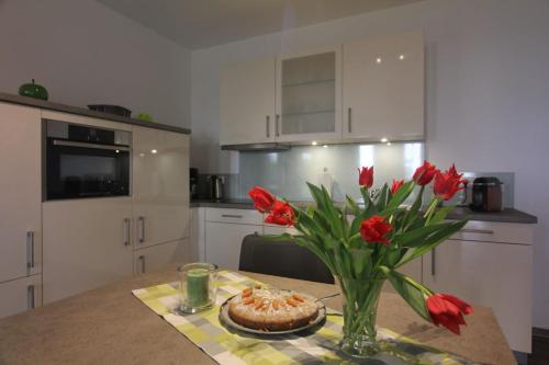 a kitchen with a table with a vase of red flowers at Ferienwohnung Kurpark in Xanten