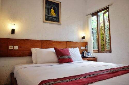 a bedroom with a large bed with a red pillow at Cempaka Borobudur Guest House in Borobudur