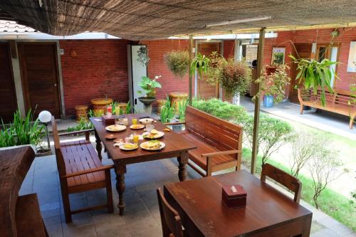 een patio met een houten tafel en stoelen bij Cempaka Borobudur Guest House in Borobudur